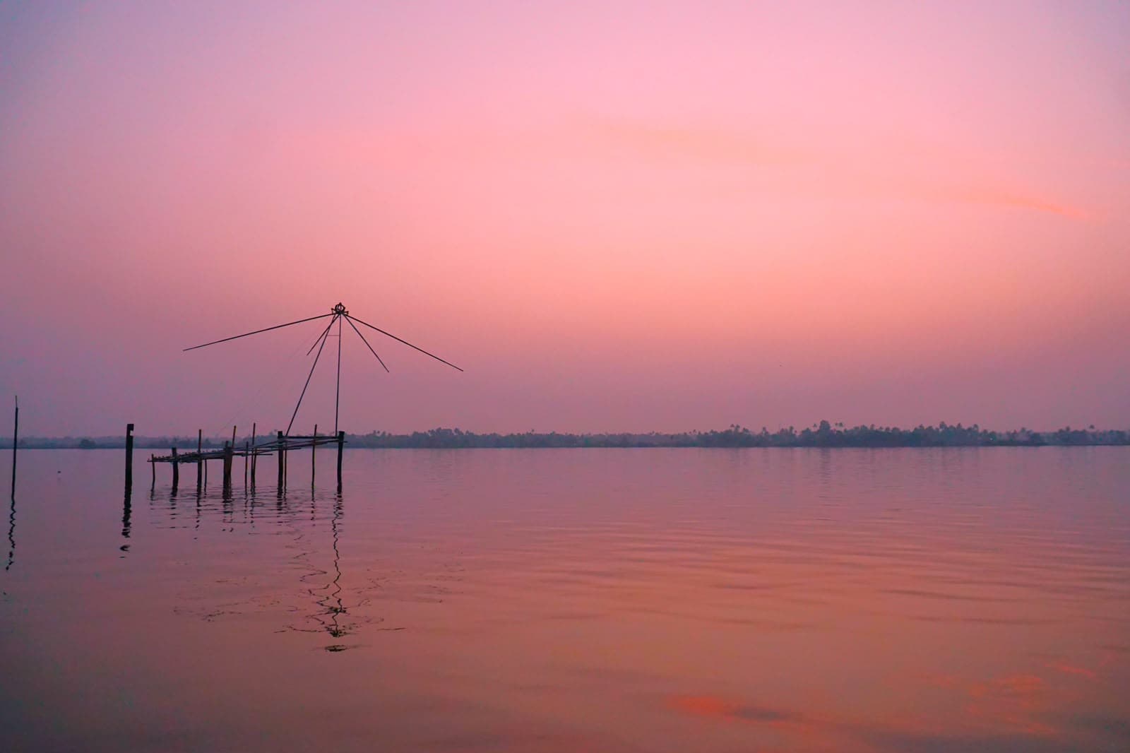 Fishing nets on a wide, glassy backwater under a soft pink evening sky.