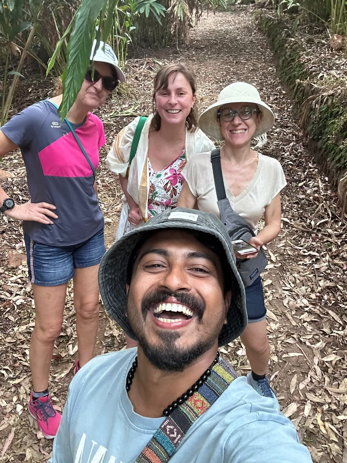 An Earthbound guide laughing on a forest trail with three travellers behind.