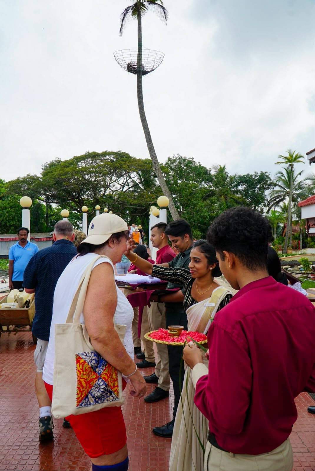 Hosts serving welcome refreshments to guests on an open terrace beneath palms.