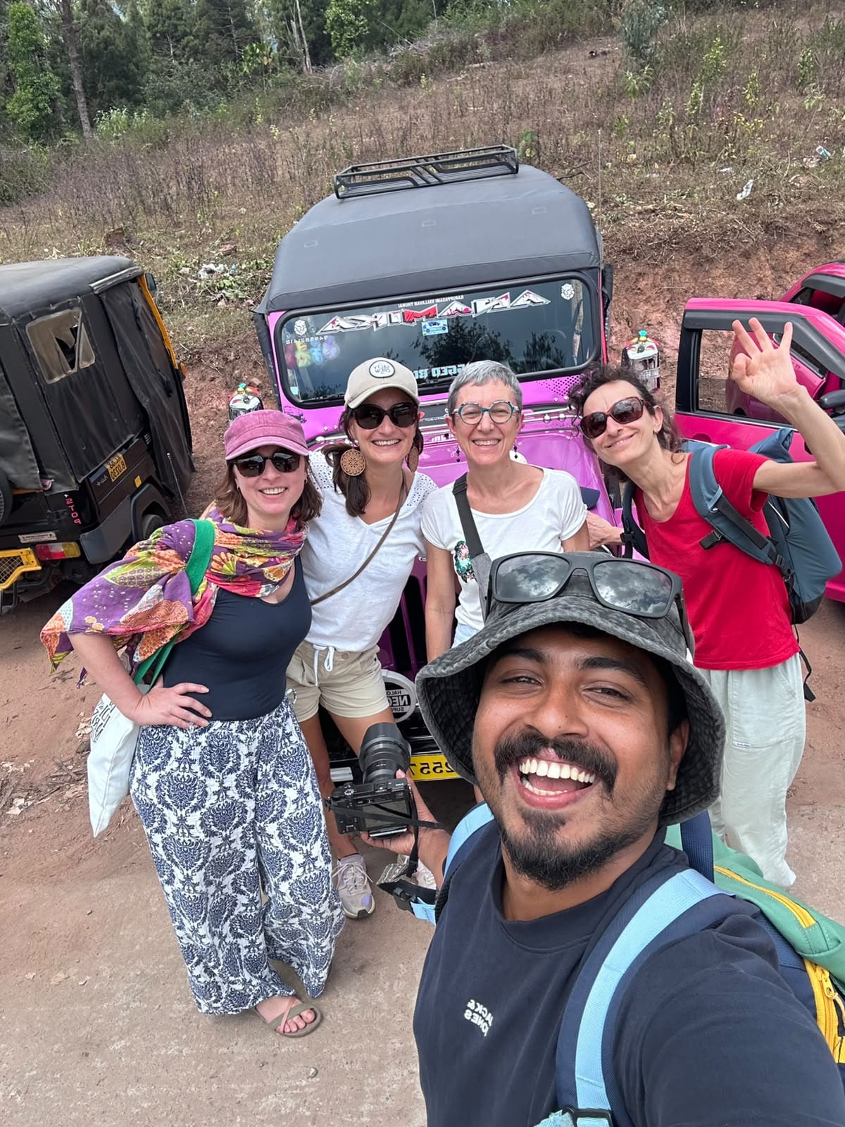Travellers gathered beside off-road jeeps on a hill road with their guide.